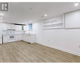 A spacious kitchen with white cabinets and a wooden floor.