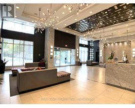 A spacious lobby with a reception desk and a large chandelier.