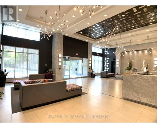 A spacious lobby with a reception desk and a large chandelier.