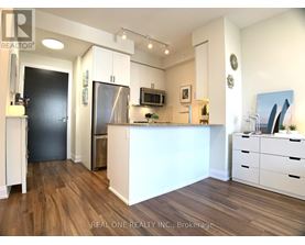 A kitchen with white cabinets and a wooden floor.