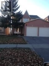 A house with a driveway and a tree in front of it.
