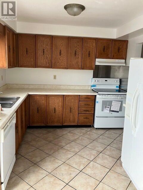 A kitchen with white appliances and brown cabinets.