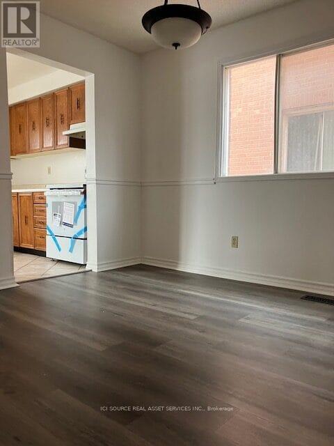 A room with wooden floors and a window with white curtains.
