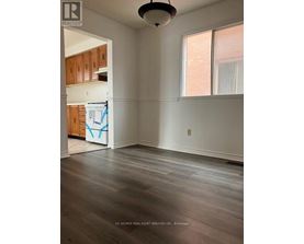 A room with wooden floors and a window with white curtains.