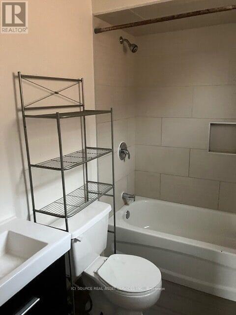 A white toilet sits in a bathroom with a white bathtub.