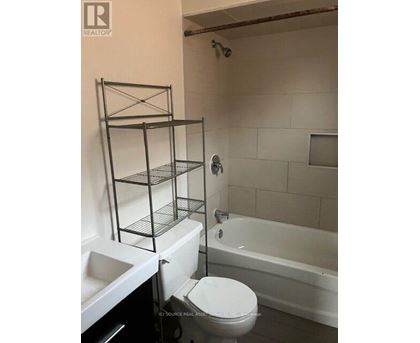 A white toilet sits in a bathroom with a white bathtub.