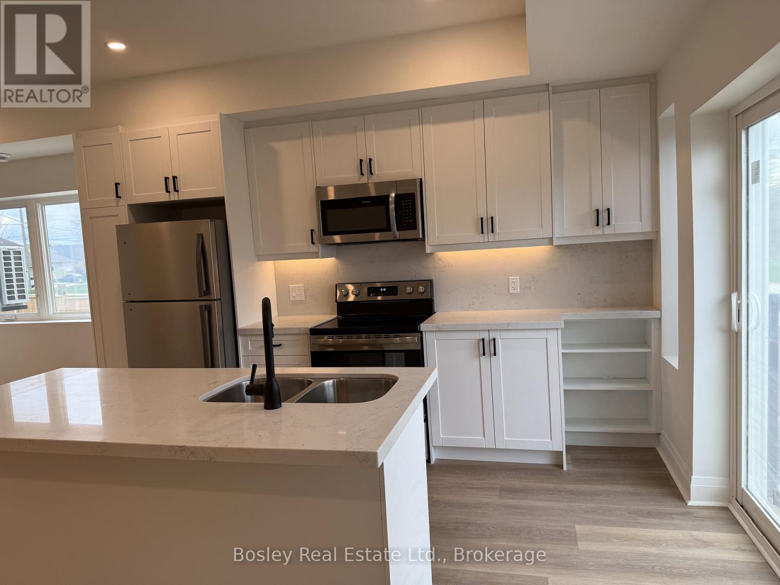 A kitchen with white cabinets and a marble countertop.