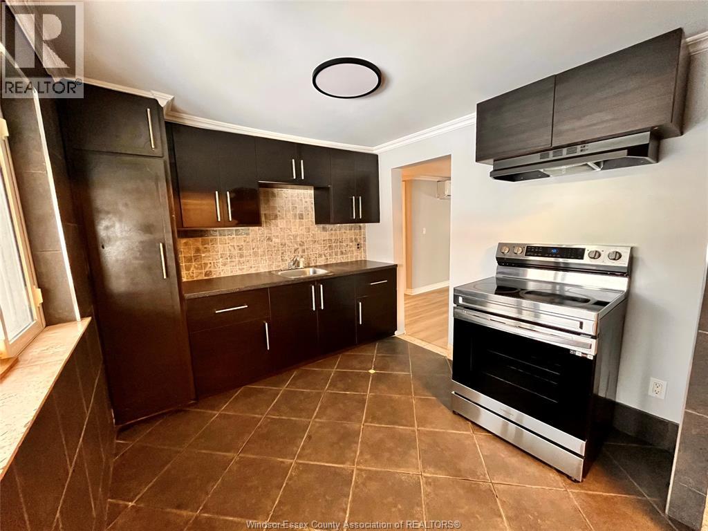 A kitchen with brown tiled floors and dark brown cabinets.
