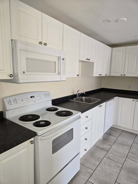A white stove and microwave in a kitchen with white cabinets.