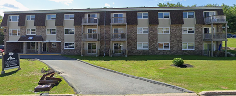 Apartment building with a black sign in front of it.