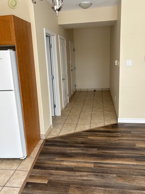 A kitchen with a white fridge and wooden flooring.