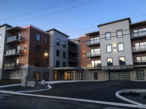 Apartment complex with a sign that says "Now Renting" and a phone number.