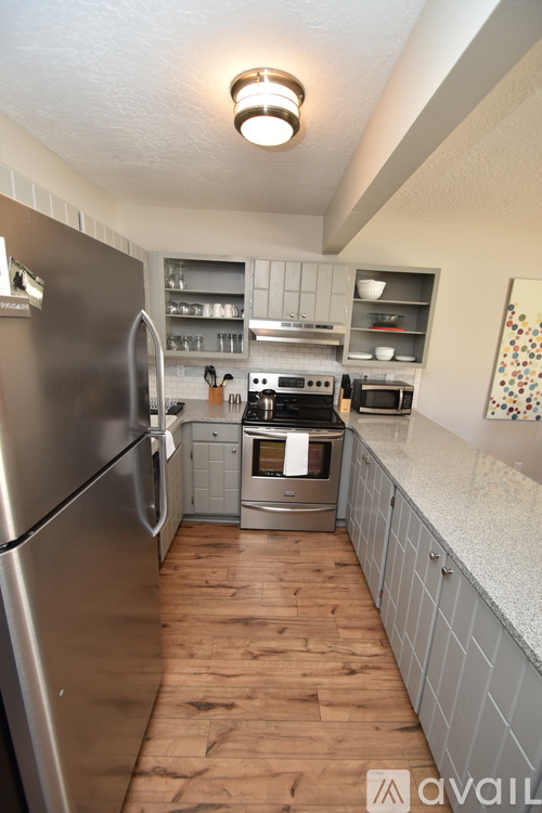 A kitchen with a stainless steel refrigerator and wooden floors.