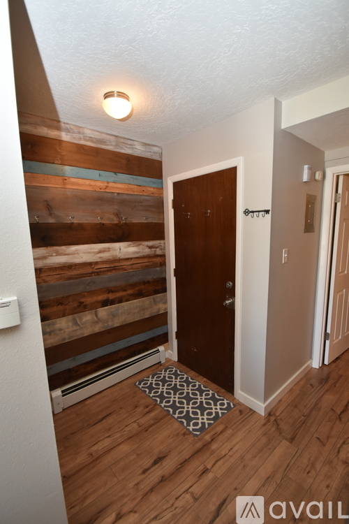 A hallway with a wooden wall and a brown door.