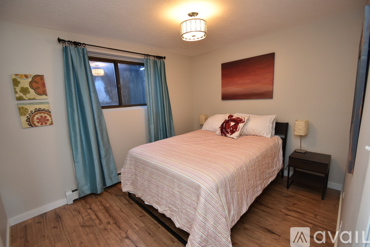 A bedroom with a bed, nightstand, and window with curtains.