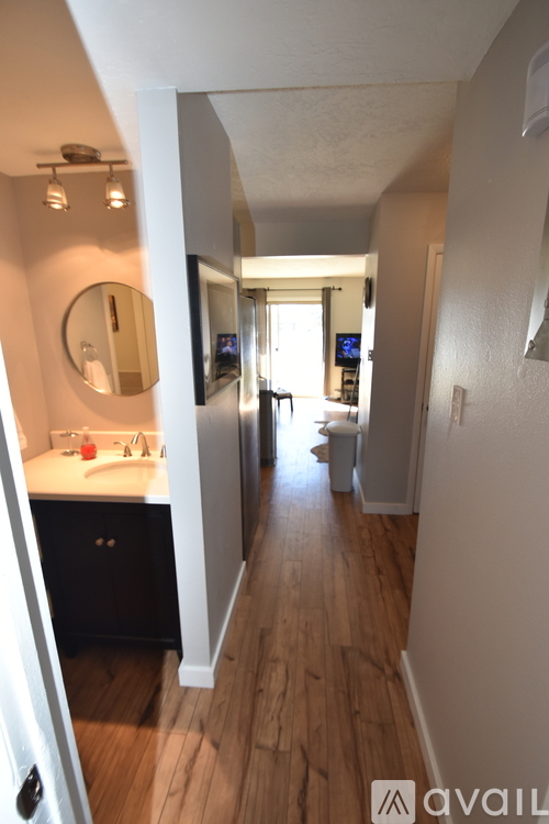 A hallway with a mirror and a door on the left.