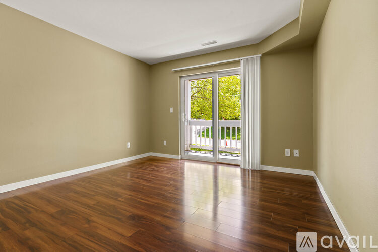 A room with wooden floors and a sliding glass door leading to a balcony.
