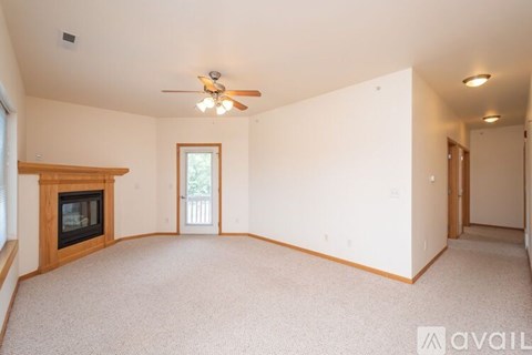 A spacious living room with a fireplace and a ceiling fan.