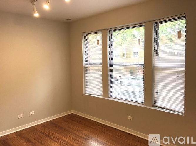 A room with wooden floors and a window with blinds.