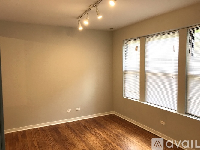 A room with wooden floors and a window with blinds.