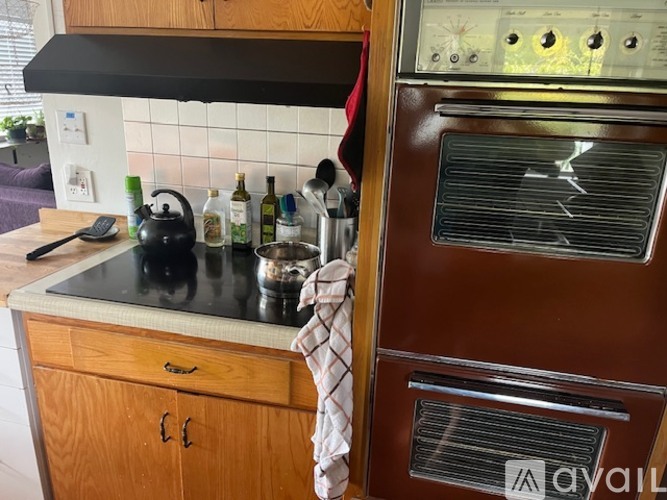 A kitchen with a black stove top and a wooden cabinet.