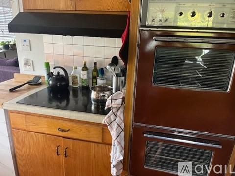 A kitchen with a black stove top and a wooden cabinet.