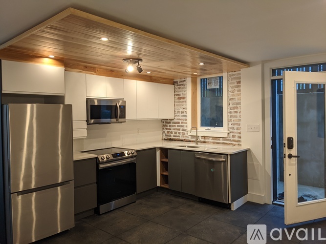 A modern kitchen with stainless steel appliances and a wooden ceiling.