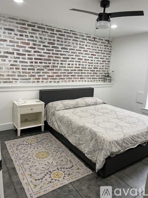 A bedroom with a brick wall and a bed with a white comforter.