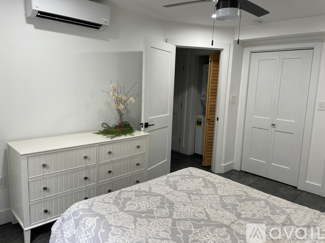 A bedroom with a bed, dresser, and a ceiling fan.