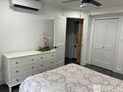 A bedroom with a bed, dresser, and a ceiling fan.