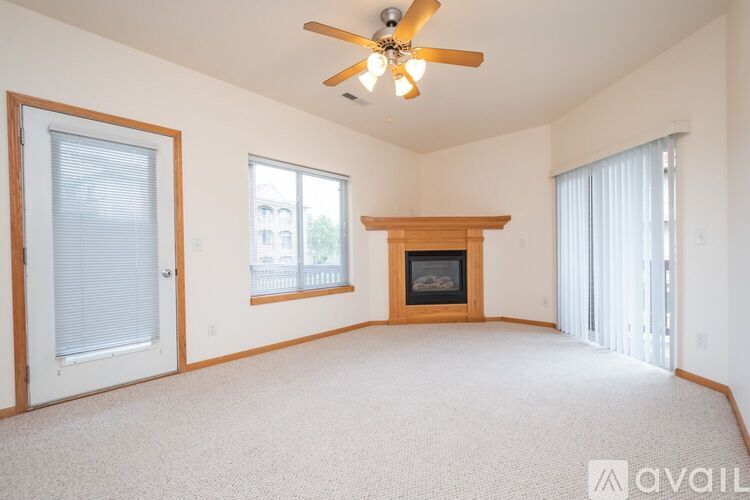 A living room with a fireplace and a ceiling fan.