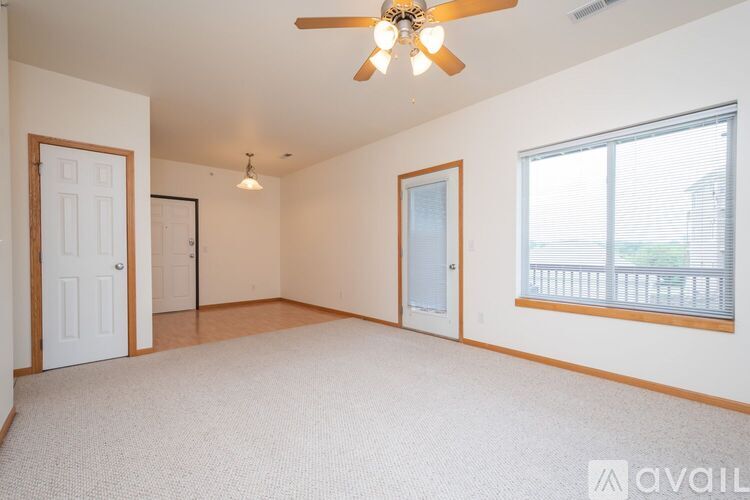 A spacious room with a ceiling fan and a window with blinds.