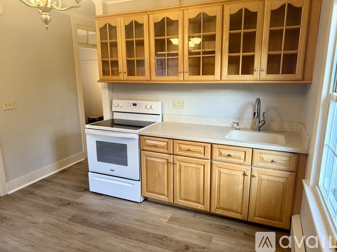 A kitchen with wooden cabinets and a white stove top oven.
