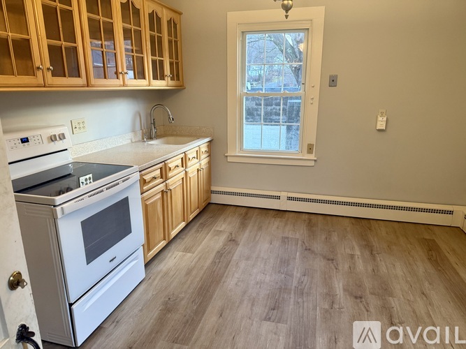 A kitchen with wooden cabinets and a white stove top oven.