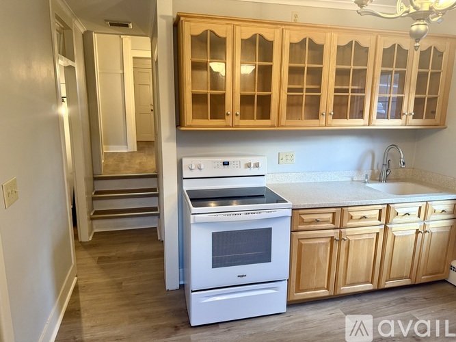A kitchen with wooden cabinets and a white stove top oven.