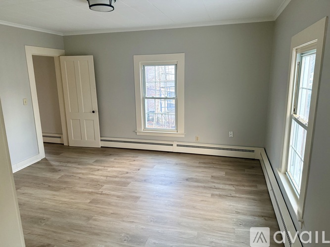 A room with a wooden floor and a window with a view of a building outside.