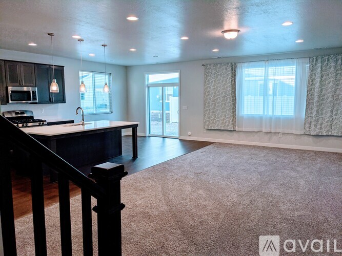 A spacious kitchen with a black countertop and a window with curtains.