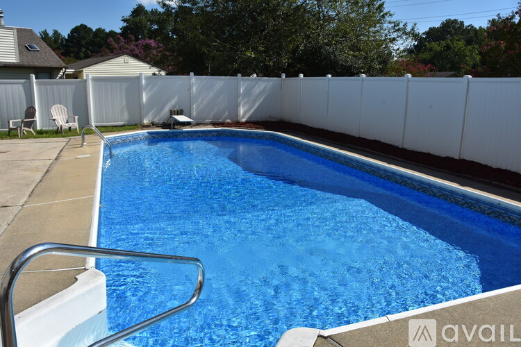 A pool with a white fence and a metal ladder.