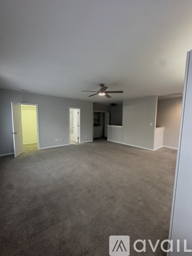 A spacious room with a ceiling fan and carpeted floor.