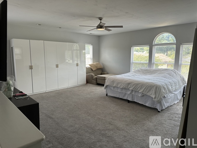 A bedroom with a bed, dresser, and a ceiling fan.