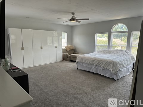 A bedroom with a bed, dresser, and a ceiling fan.