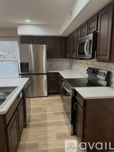 A kitchen with dark wood cabinets and a stainless steel refrigerator.
