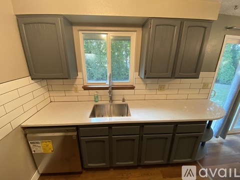 A kitchen with a sink and cabinets under a window.