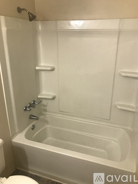 A white bathtub with a shower head and faucet.