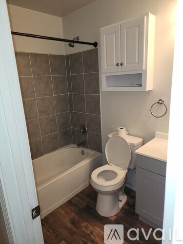 A bathroom with a toilet, tub, and cabinet.