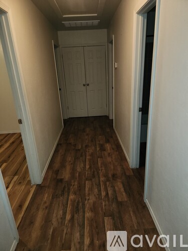 A hallway with wood flooring and white walls.