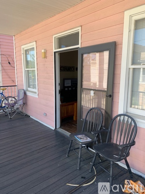 A pink house with a black chair and a bicycle.