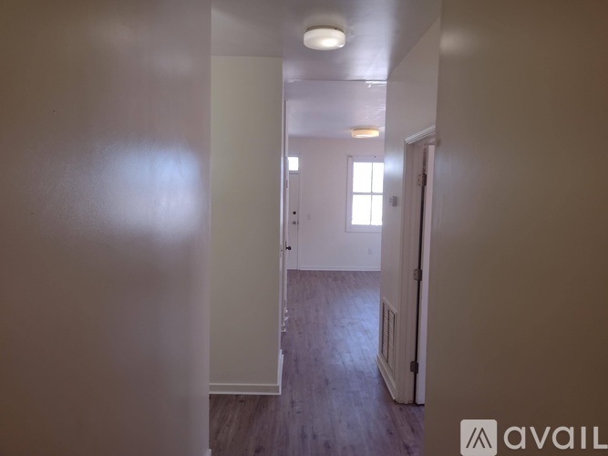 A hallway with a door on the right and a window on the wall.