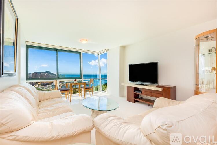 A living room with white furniture and a view of the sea through the windows.