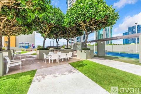 A patio with a table and chairs is surrounded by trees and has a pool in the background.